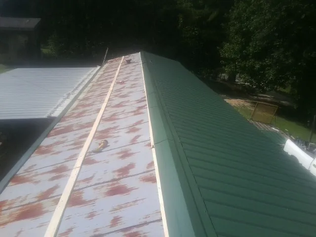 Old rusted panels beside newly installed green metal roofing — Wind Damage Roof Repair by Roofing Brothers in Pleasant Hill
